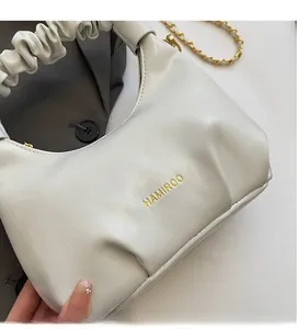 Gros plan détaillé d'un sac à main plissé crème avec chaîne dorée et logo élégant