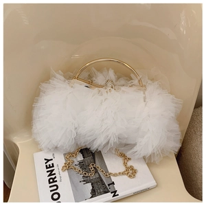 Close-up of elegant white lace tulle evening bag with gold handle and crystal ball clasp