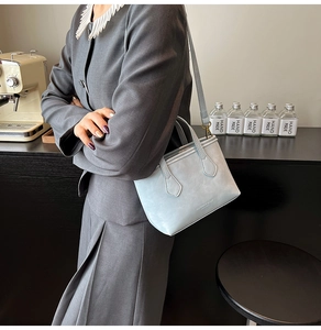 Detail of light blue crossbody bucket bag shown in a stylish cafe setting for women