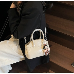 Borsa Boston chic in pelle cerata bianco crema con ciondolo in una scena di pendolare