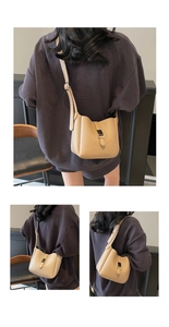 Detail showing the adjustable shoulder strap and metal buckle on the cream bucket bag