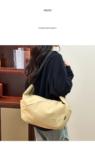 Detail of minimalist beige dumpling bag with adjustable wide strap and metal logo