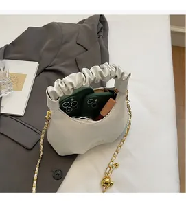 Détail intérieur d'un sac à main blanc plissé avec chaîne dorée et rangement de téléphone