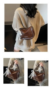 Detail view of brown vintage leather pillow bag with elegant pearl lace bow charm