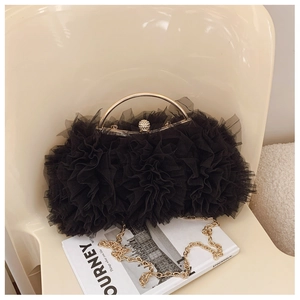 Close-up of black lace mesh handbag with gold hardware and sparkling diamond clasp