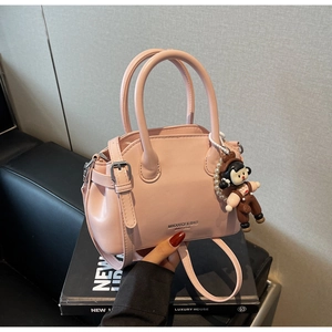 Dettaglio della borsa in pelle rosa con ciondolo a bambola e catena di perle chic