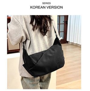 Detailed view of the embossed MS logo on a large black dumpling-style messenger bag