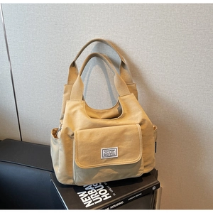 Detail of minimalist beige canvas shoulder bag with multi-pocket design on books