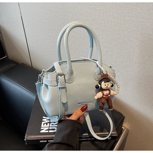 Borsa a mano azzurra in pelle cerata con catena di perle e ciondolo a bambolina