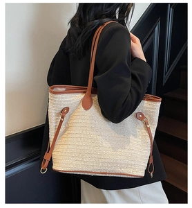Detail of woven straw tote bag featuring brown leather trim and metallic side buckle