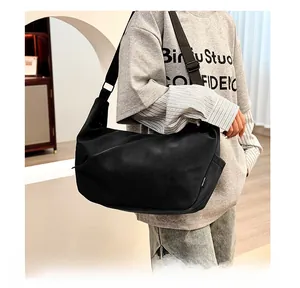 Detail of black minimalist dumpling bag showing the logo and wide nylon shoulder strap