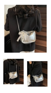 Detail view of silver leather crossbody bag with pearl chain and lace bow decoration
