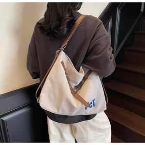 Detail showing high-capacity canvas tote bag with brown leather straps and CT embroidery