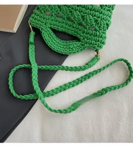 Detail of green hand-crocheted woven bag featuring gold metal hooks and thick cotton rope