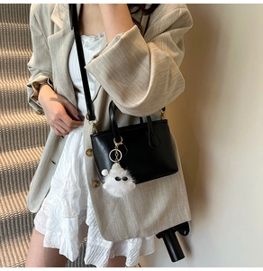 Chic black leather bucket bag with plush charm styled on a beige blazer and lace dress
