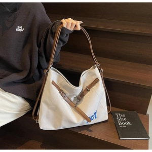 Detail of a large canvas tote bag with brown leather handles on wooden stairs