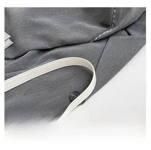 Detailed close-up showing grey twill fabric texture and white leather shoulder strap detail