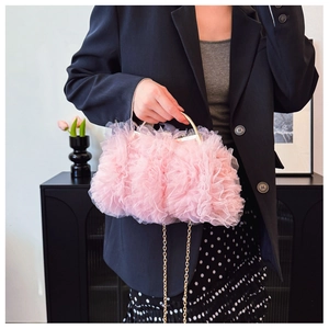 Close-up of pink ruffled mesh handbag with gold circular handle and delicate chain strap