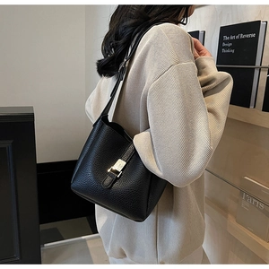 Detail shot of black litchi pattern leather bucket bag with silver buckle and soft texture