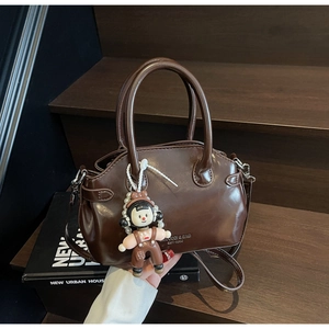 Dettaglio della borsa Boston in pelle marrone scuro con ciondolo di perle su scale in legno