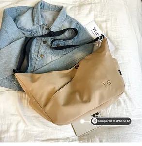 Nylon messenger bag in khaki showing size comparison with an iPhone 12 mobile phone