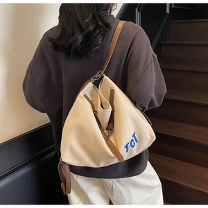 Detail of canvas tote bag showing cream fabric with brown leather straps and TCI logo