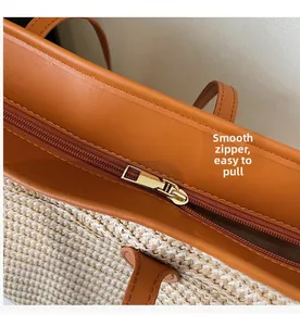 Close-up of golden metal zipper and brown leather trim on woven straw tote bag