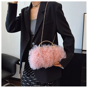 Pink layered mesh evening clutch with gold handles and chain shown in lifestyle setting