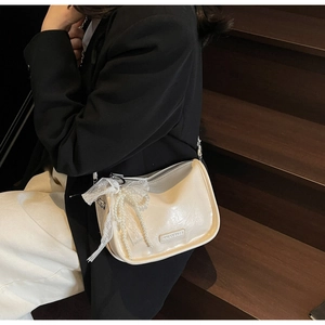 Detail of cream leather pillow bag with lace bow and pearl tassel on stairs