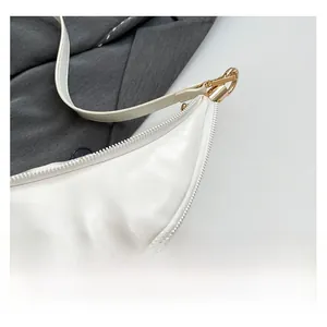 Close-up of white crescent underarm bag showing premium faux leather texture and golden buckles