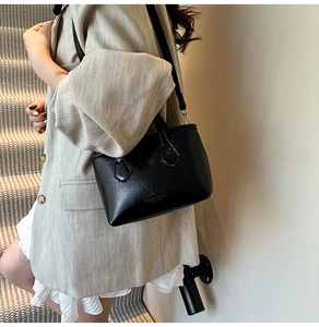 Detail view of the black bucket bag with adjustable strap and metallic gold buckles