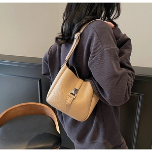 Detail of warm camel lychee textured leather shoulder bag with metallic snap closure