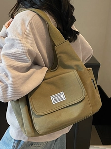 Minimalist olive green canvas shoulder bag with large capacity and wide strap shown on model