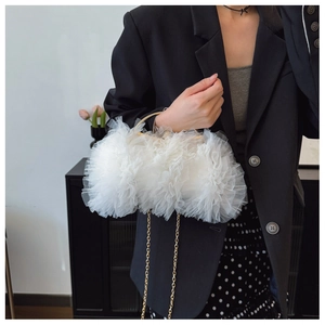 Close-up of white ruffled lace gauze handbag featuring gold metal handle and chain strap