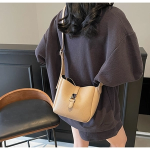 Detail view of khaki lychee grain leather bucket bag featuring a secure metal buckle closure