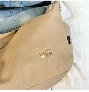 Detail of beige nylon crossbody bag with golden MG embroidery and branded side label tag