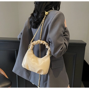 Vue détaillée du sac plissé beige avec bandoulière chaîne sur veste grise