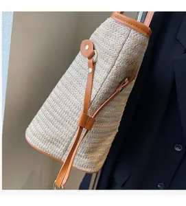 Detail of woven straw tote bag featuring brown leather trim and high-quality craftsmanship