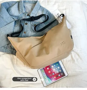 Large khaki crossbody dumpling bag shown next to an iPad for size comparison