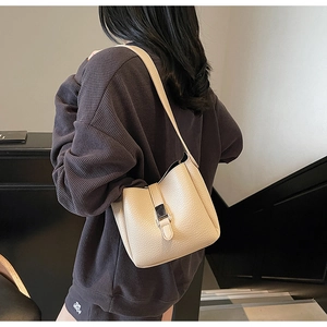 Detail of apricot litchi texture bucket bag with silver metal buckle on a shoulder