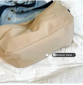 Detailed bottom view of large beige nylon crossbody bag with durable metal logo