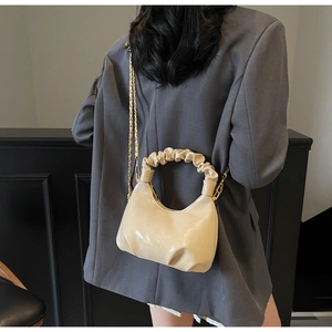 Détail du sac à main beige avec poignée froncée et bandoulière en chaîne dorée