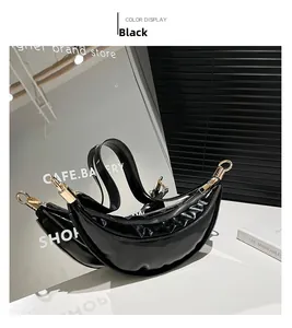 Detail of a black crescent shoulder bag in glossy patent leather with gold hardware