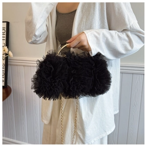 Detail of black ruffled lace mesh evening bag with golden metal handle and chain strap