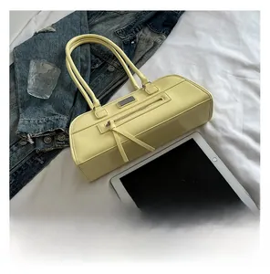 Détail d'un sac bowling jaune rectangulaire avec de fines poignées et une poche zippée