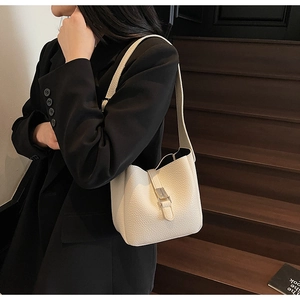 Detail of cream white litchi grain leather bucket bag with silver clasp and strap