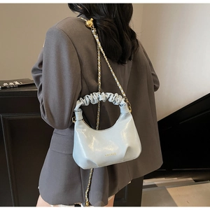 Détail du sac plissé bleu clair brillant avec bandoulière à billes métalliques dorées