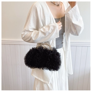 Detail of elegant black pleated mesh handbag featuring a gold metal handle and chain