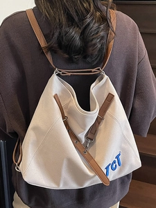 Minimalist canvas tote bag with brown leather straps and blue TCT embroidery on model