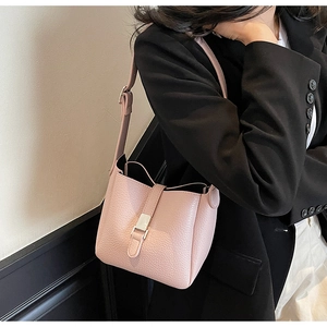 Detail of light pink lychee texture bucket bag with metal buckle and leather shoulder strap